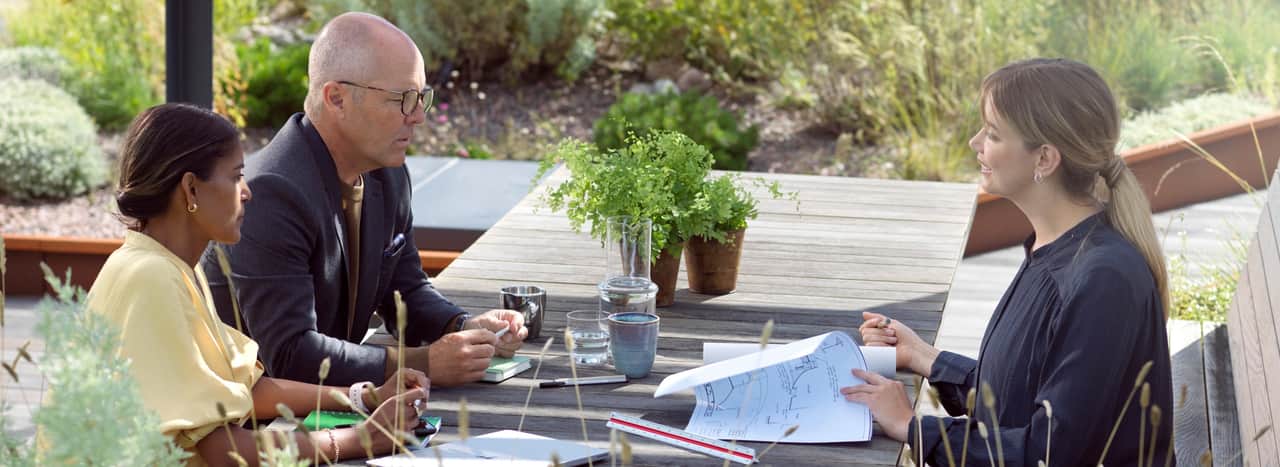 Tre personer som har ett möte utomhus.