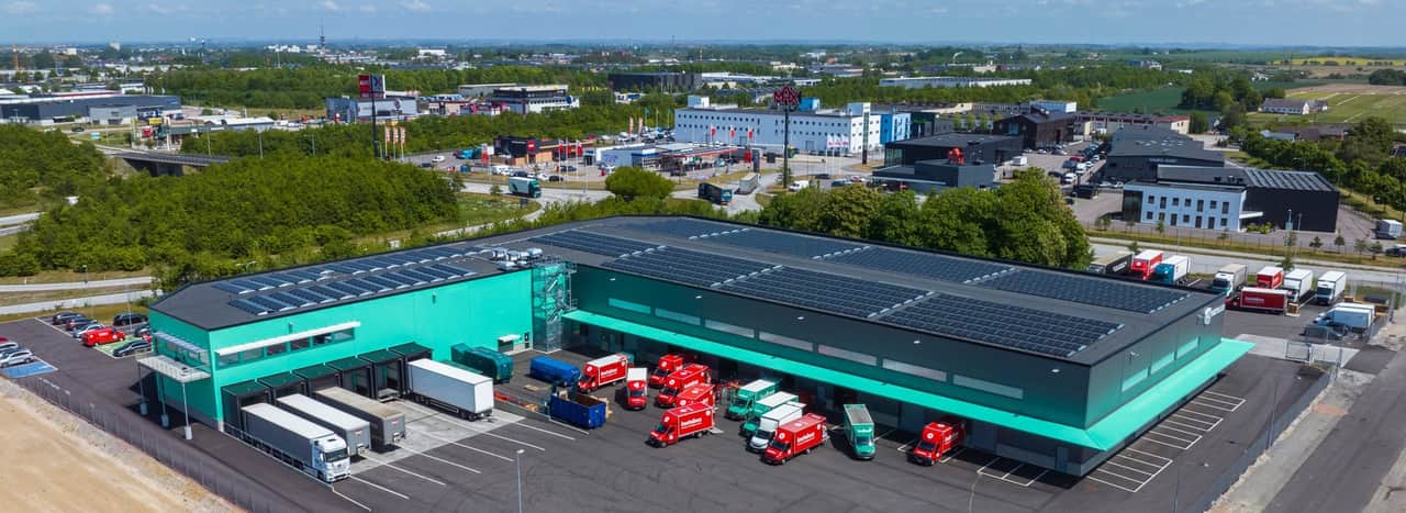 Visionsbild av fastigheten med lastbilar utanför.