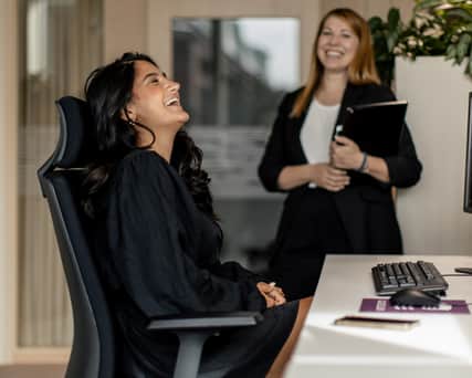 Två kvinnor på kontor skrattar