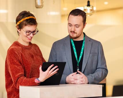Två personer står och tittar på en ipad.
