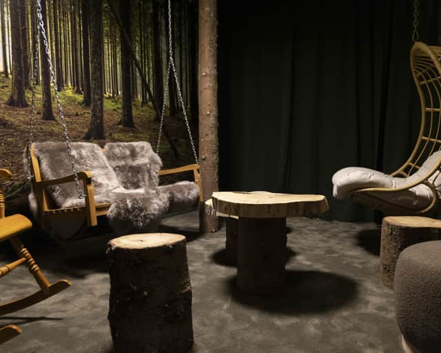 Ett skogsrum med en fototapet med skog, hängande gungor i trä, bordsskiva från en trästam, mysig varm belysning för avslappning.