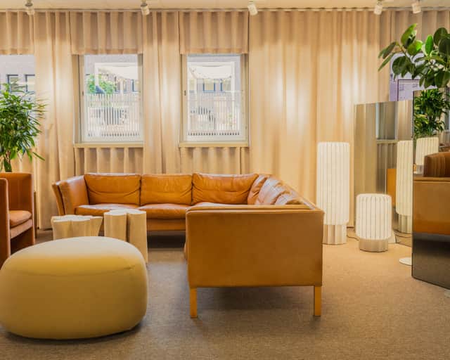 Stor yta inomhus med soffor, reception, människor som sitter vid bord