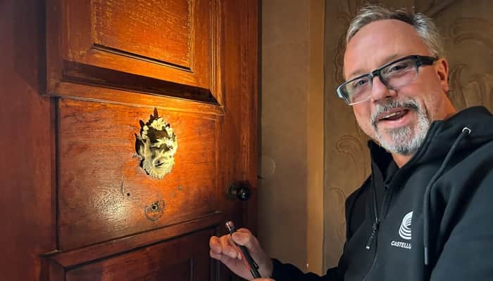 En man håller i en skruvmejsel framför en trädörr.