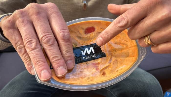 En man som håller en behållare med mat i sina händer.