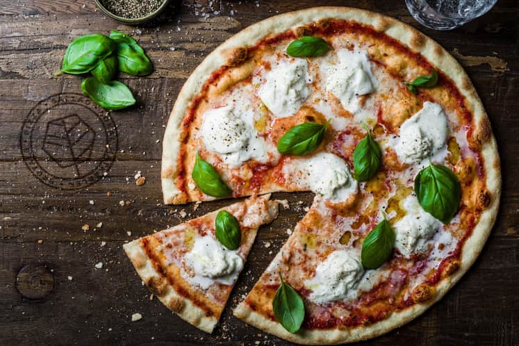 Färdiggräddad pizza på träbord med färska örter