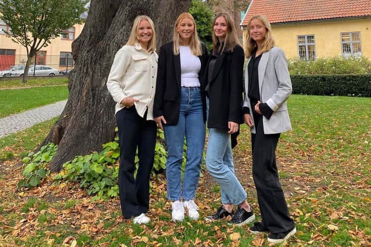 Fyra personer framför ett träd.