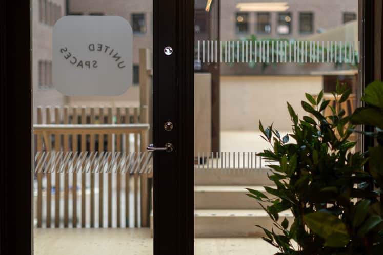 En dörr med texten United Spaces som vätter ut mot en innergård