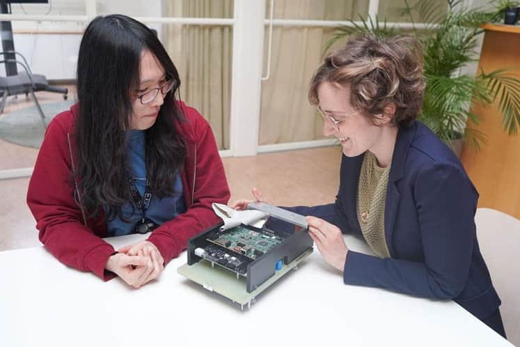 Två kvinnor sitter vid ett skriv bord med ett mätinstrument