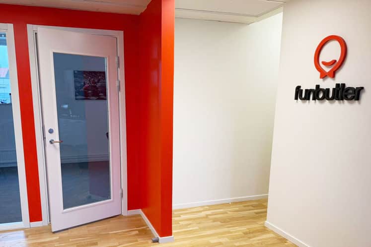 Bilden visar en dörr, en röd mellanvägg och en vägg där Funbutlers logo finns