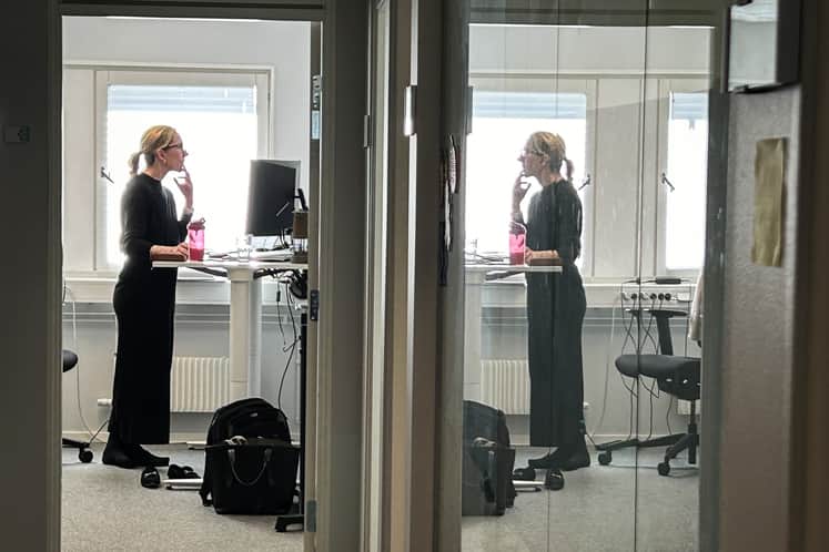 En person står på ett kontor och arbetar vid sitt skrivbord.