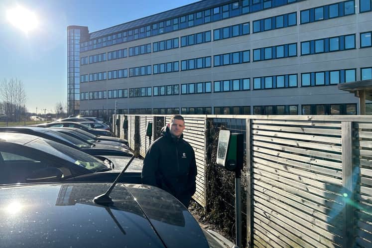 En castellumanställd står vid en laddstation på en parkeringsplats.