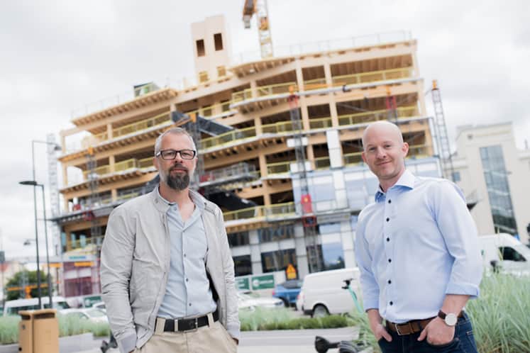 Arktitekterna framför byggplatsen.