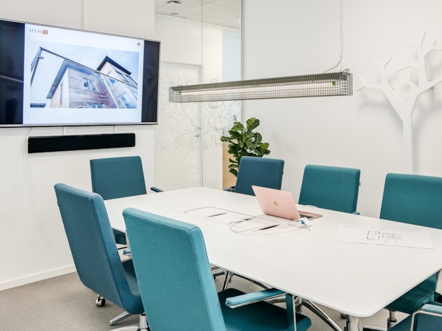 Mindre konferensrum med stolar runt ett bord och en tv-skärm på väggen