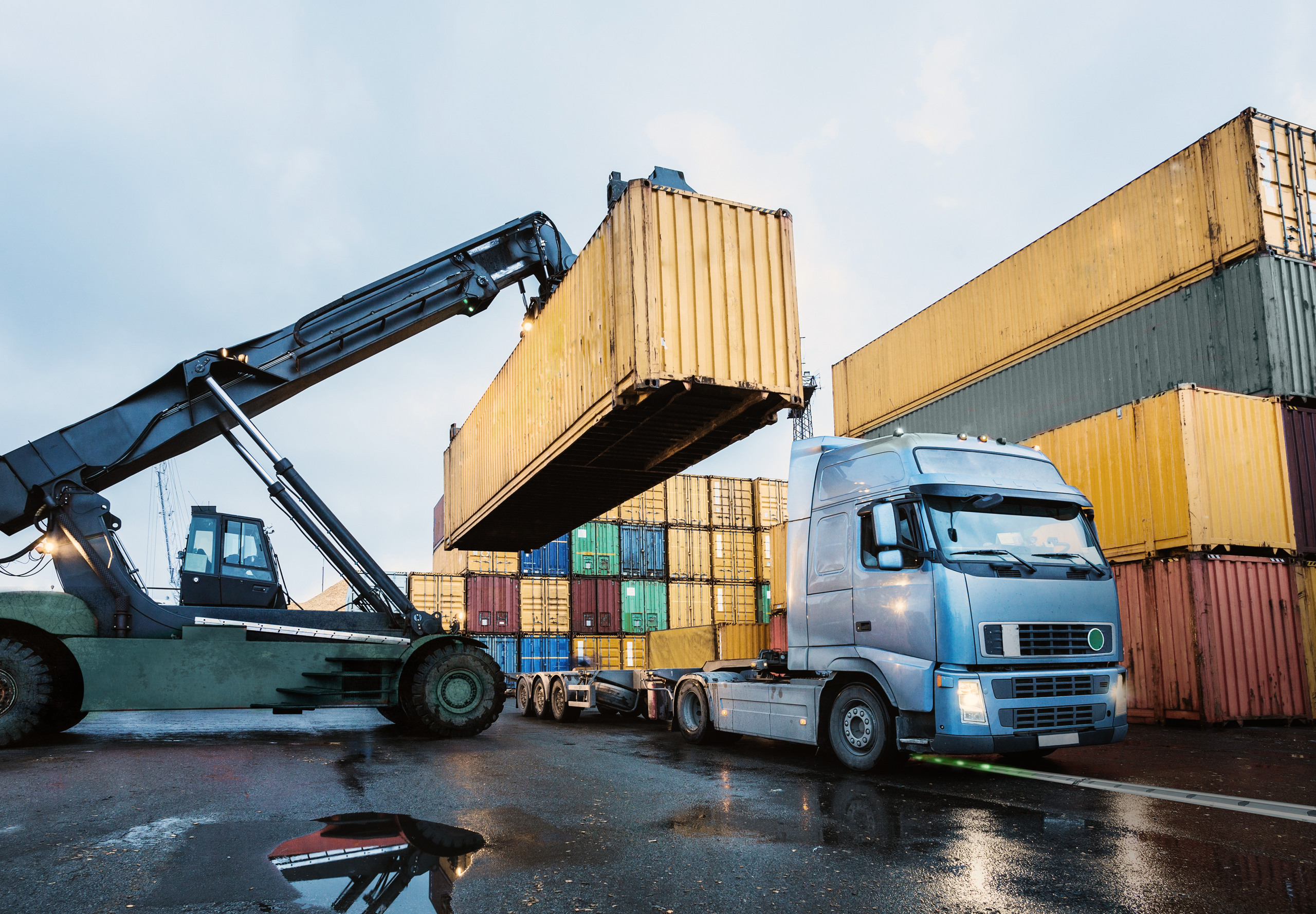 Lastbil och flera containrar, en container lastas på lastbilen