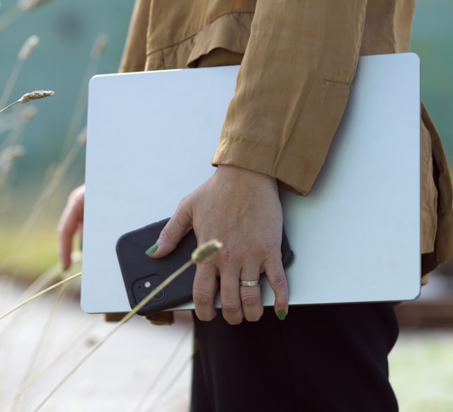 Person som håller en laptop och telefon i handen.