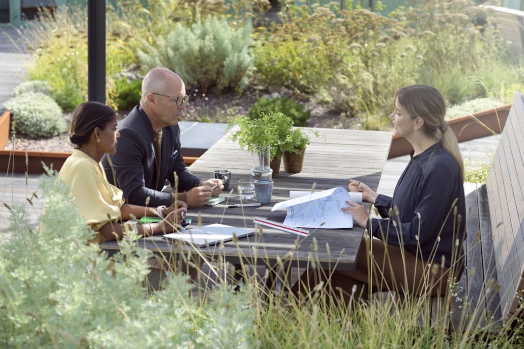 Tre personer som jobbar utomhus vid ett bord.
