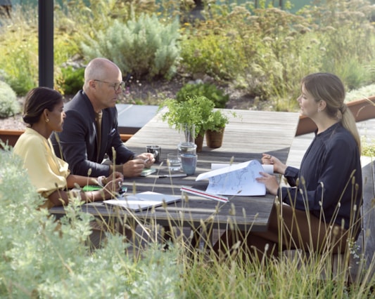 Tre personer som jobbar utomhus vid ett bord.
