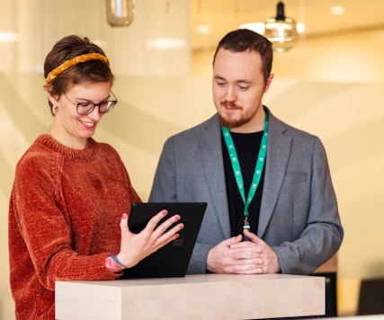 Två personer står och tittar på en ipad.