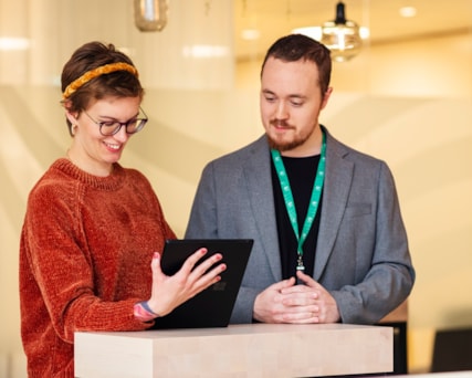 Två personer står och tittar på en ipad.