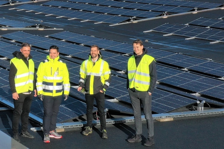 Fyra personer på ett tak med solpaneler.