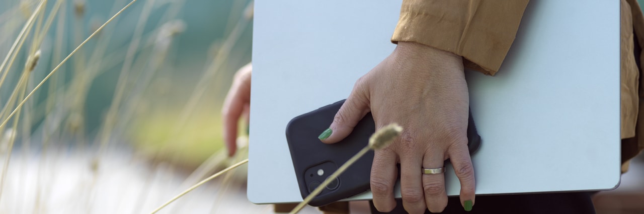 Persons hand som håller i dator och telefon.