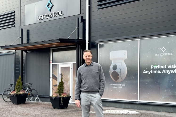 Man klädd i gråa kläder som står utomhus framför entrén till företaget