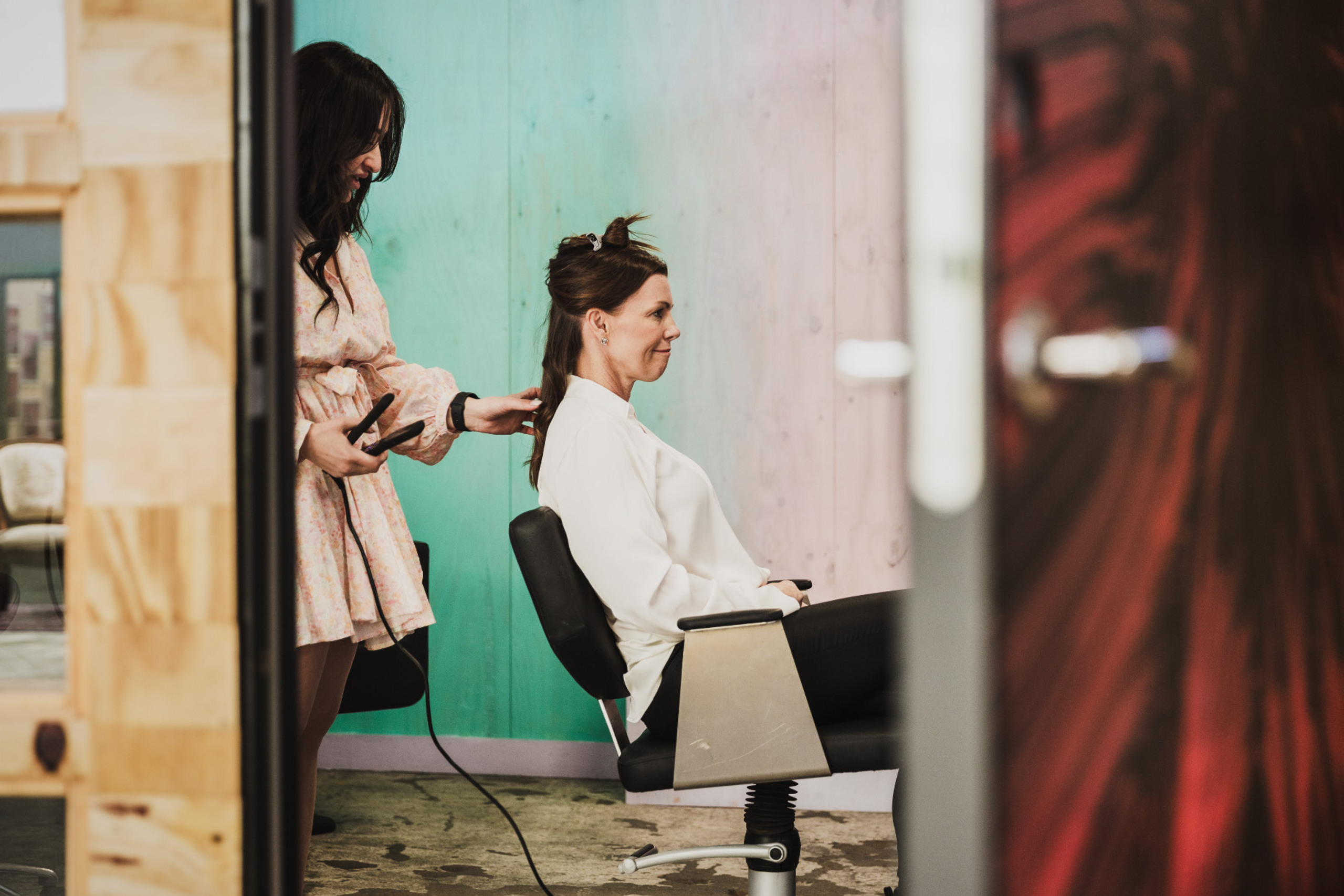 En person som sitter i en frisörsalong med en frisör bakom sig.