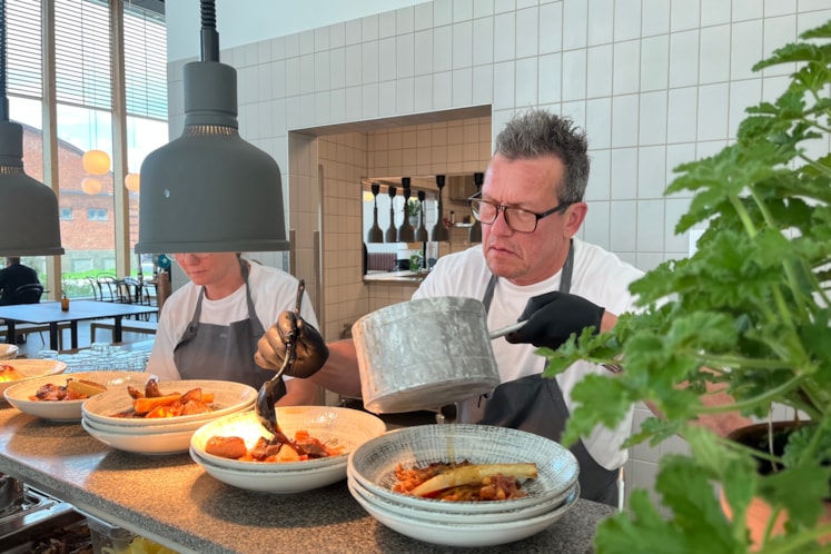 I restaurang, en man häller upp mat på en tallrik 