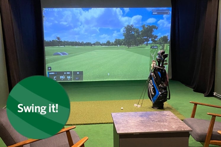 Ett rum med golfklubbor framför en skärm med golfbana.