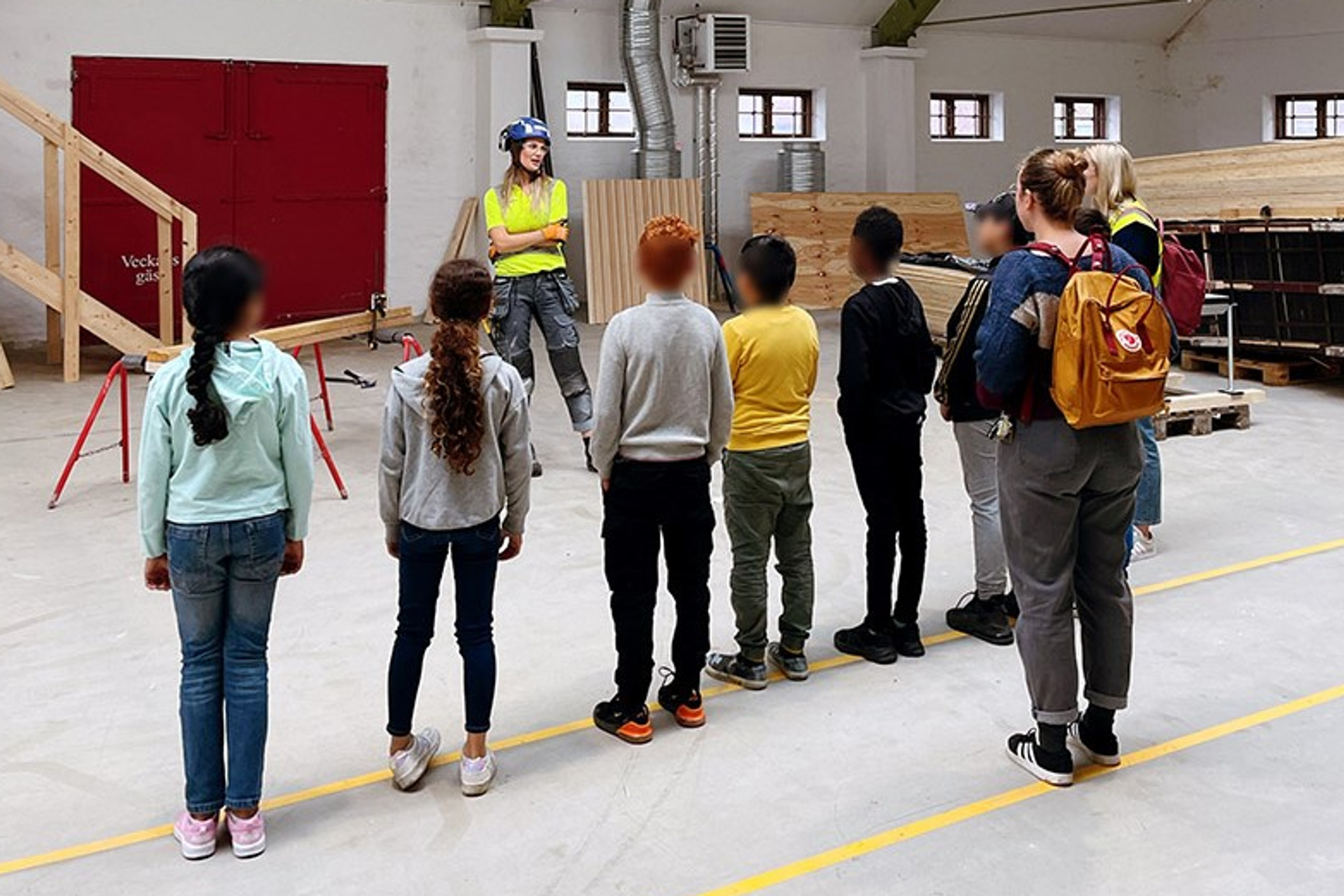 En grupp barn framför en person med gul skyddsväst.