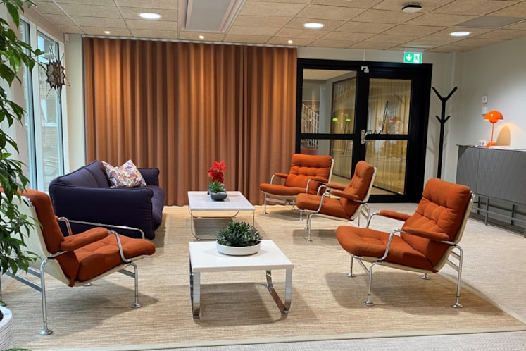 Fyra orangefärgade fåtöljer i en lounge