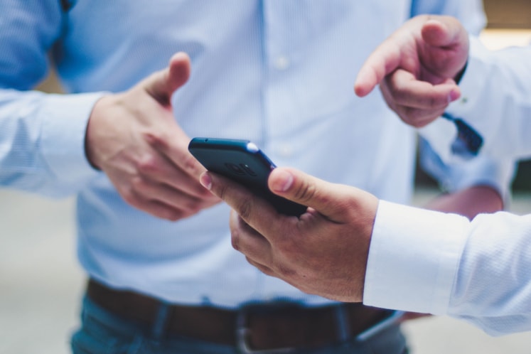 Två personer som pekar på en telefon.