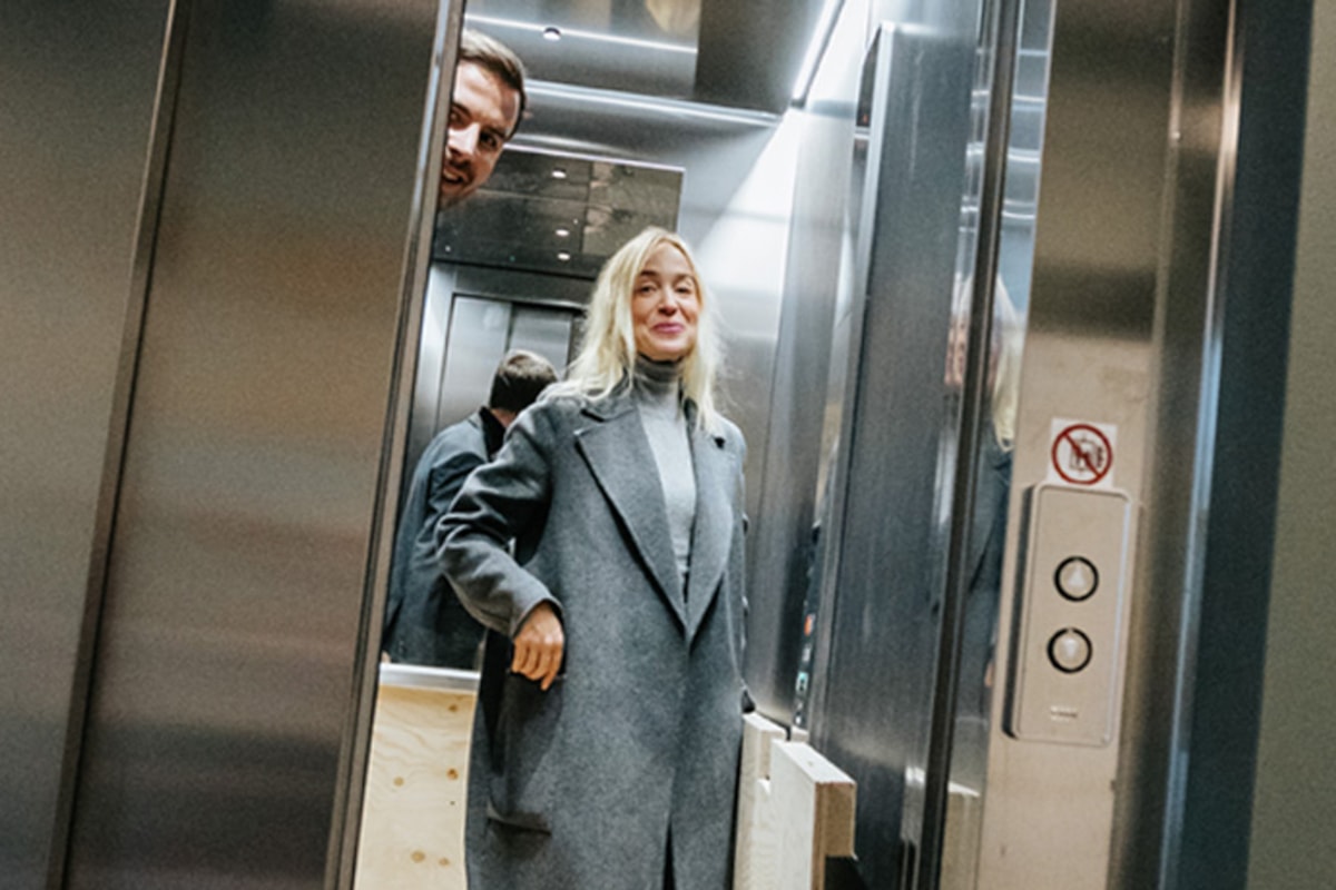 Charlotta står inne i en hiss.