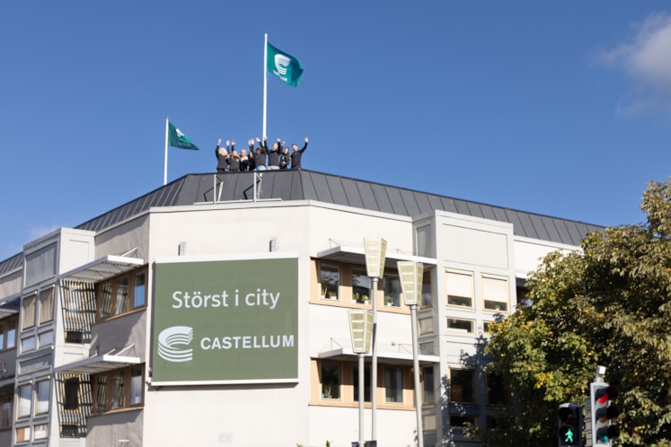 Människor uppe på taket till en fastighet med skylten Störst i city.