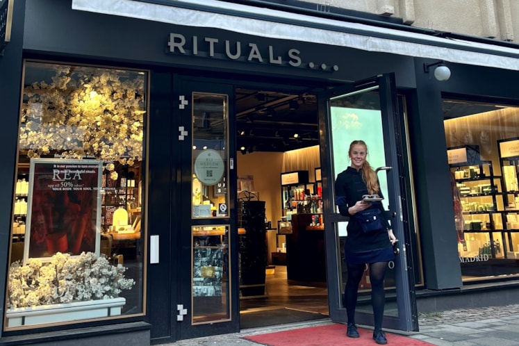 En anställd person på Rituals går ut genom entredörren på en röd matta